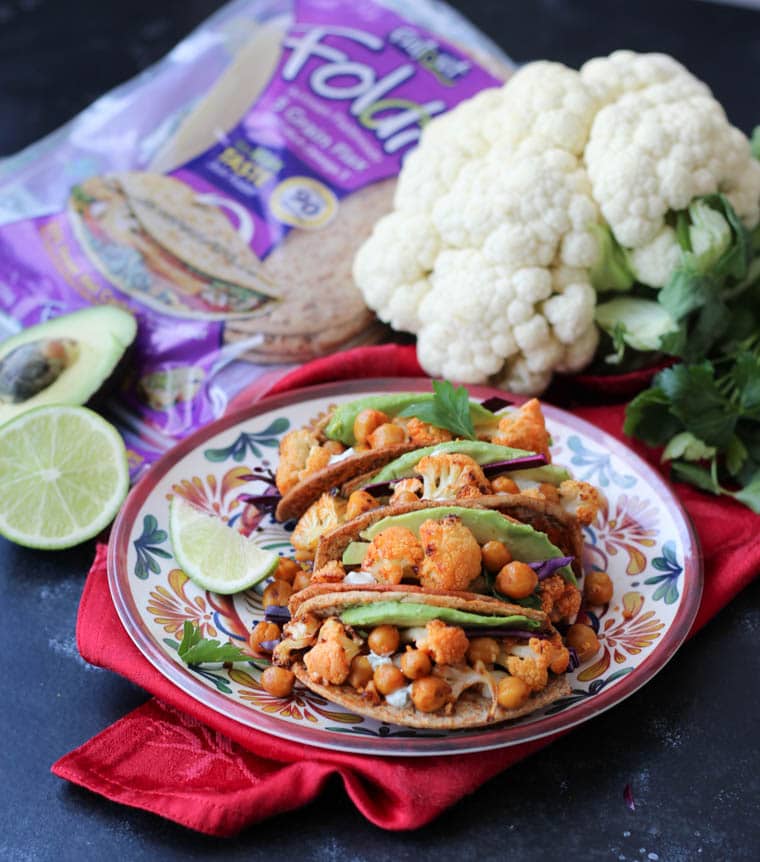 Vegan buffalo cauliflower and chickpea tacos in a colourful bowl garnished with lime.