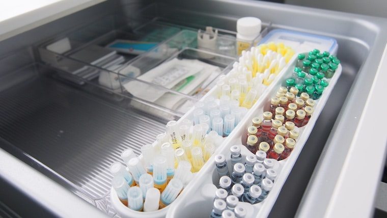 Needles and blood samples in a medical tray.