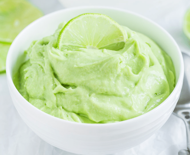 Green nice cream in a white bowl garnished with a lime slice. 