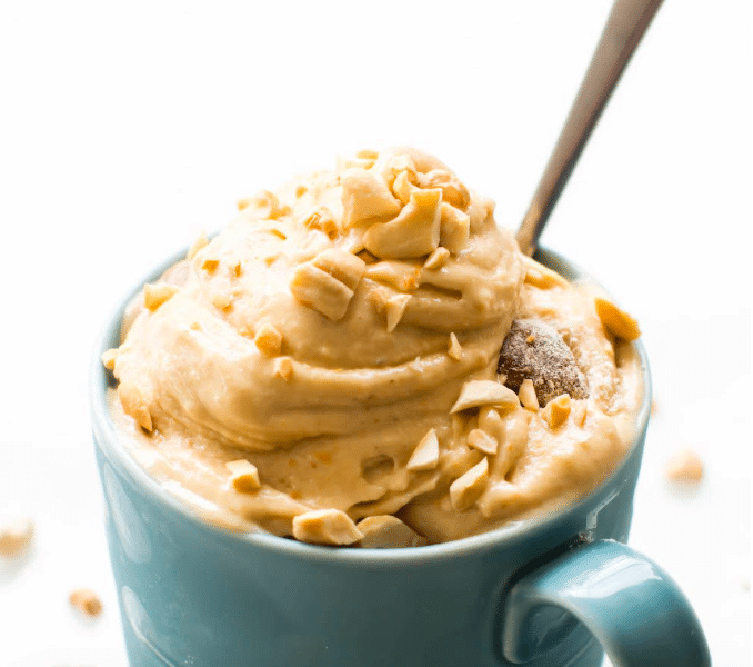 Peanut butter nice cream in a blue mug with a spoon.