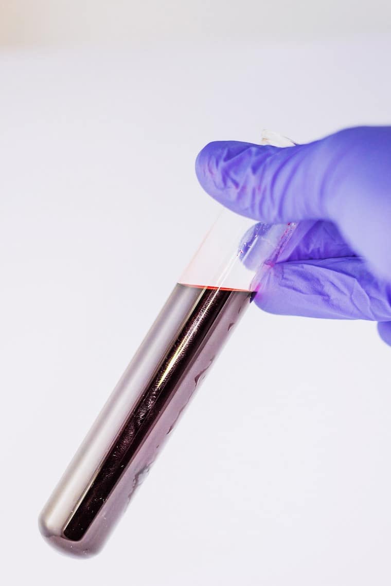 A hand holding a test tube with liquid inside.