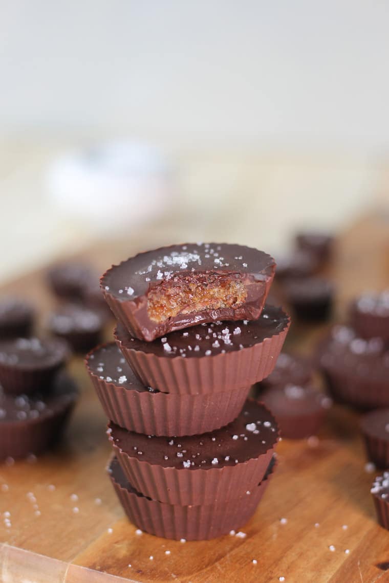 close up of a stack of vegan tahini caramel chocolate cups garnished with sea salt 