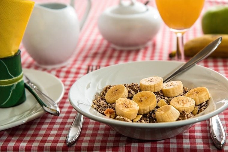 A table topped with a plate of granola and bananas.