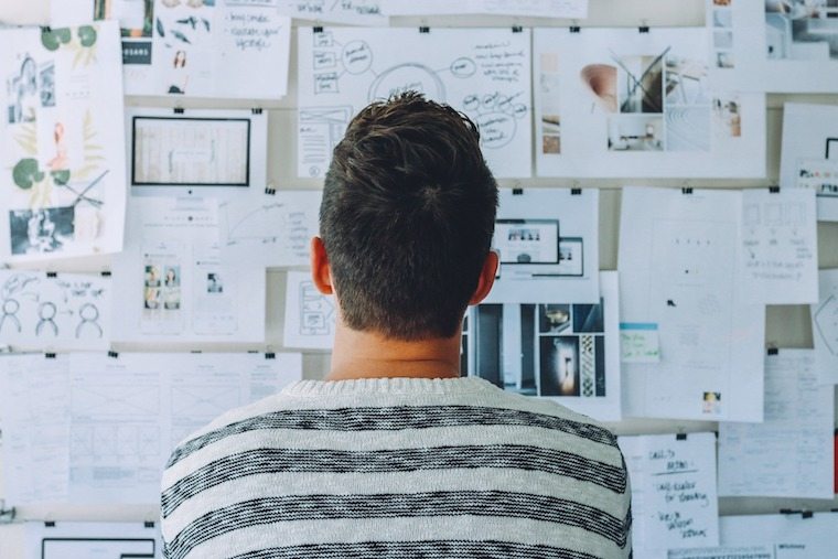 A man looking at a wall of paper.