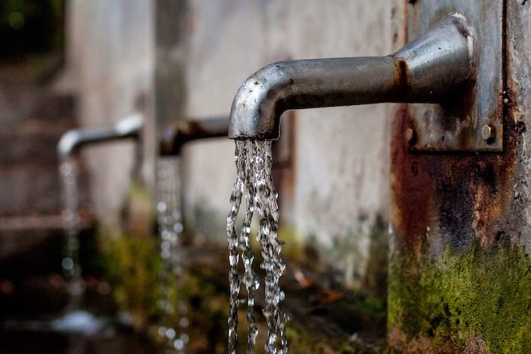 A close up of a metal tap with water coming out.