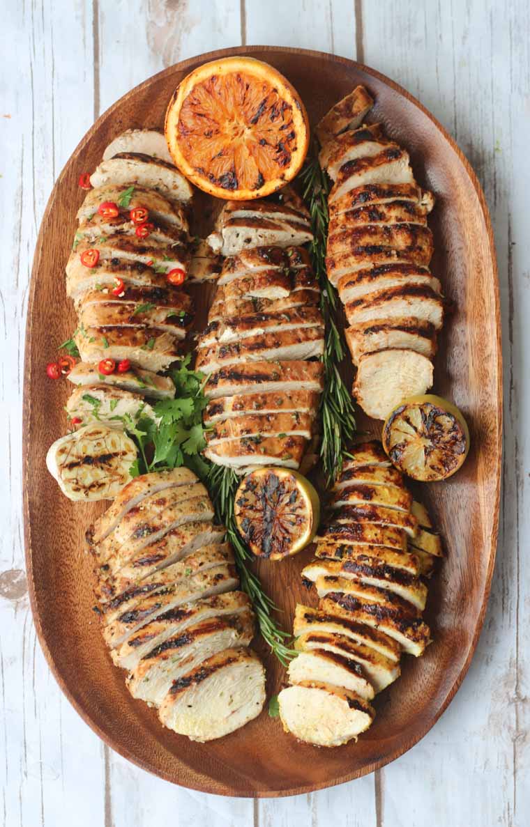 birds eye view of grilled marinated chicken breasts five ways on a wooden serving board