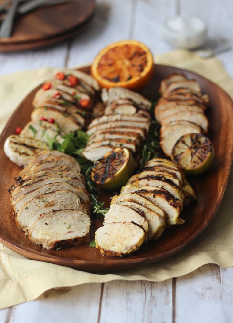 five flavours of grilled and marinated chicken breasts on a wooden serving board