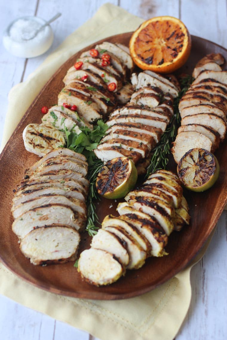 grilled chicken breasts five different ways on a wooden serving board