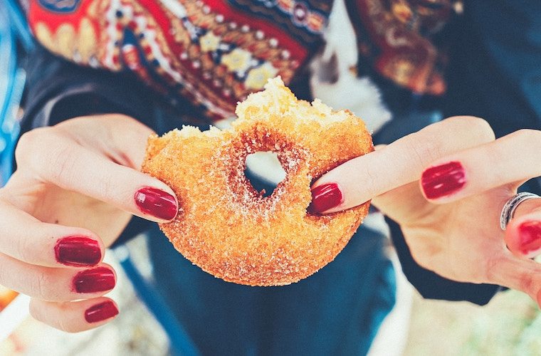 A close up of a person holding a doughnut.