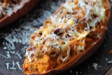 A close up of a baked sweet potato with caramelized onion and apple.