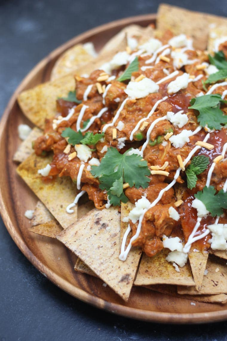 A close up of a plate of butter chicken nachos.