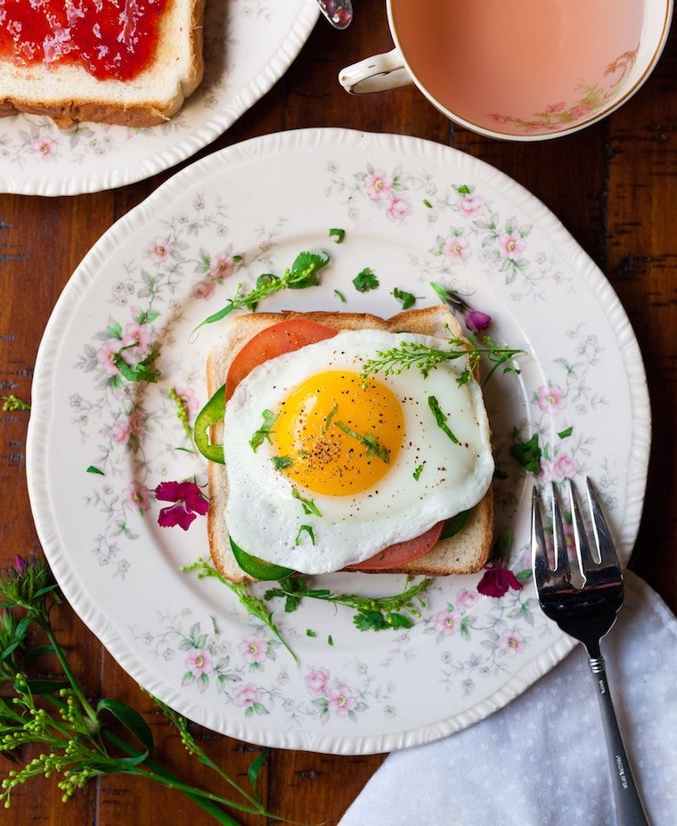 A plate on a table with a toast with an egg on top.