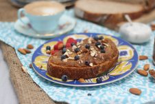 A photo of a blue plate with salted caramel almond butter spread on top with blueberries on top.