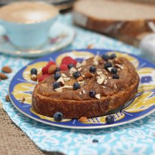 A photo of a blue plate with salted caramel almond butter spread on top with blueberries on top.