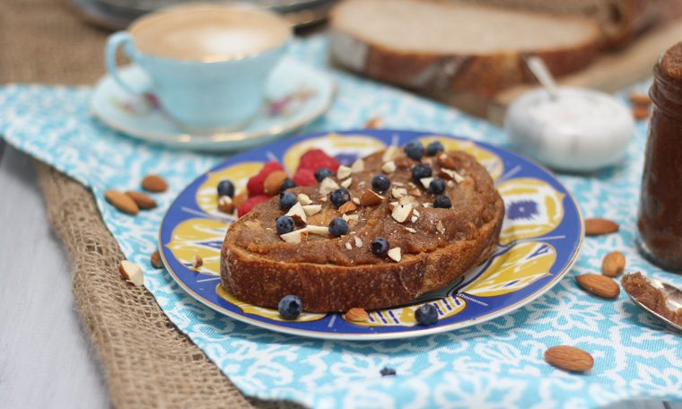 A photo of a blue plate with salted caramel almond butter spread on top with blueberries on top.