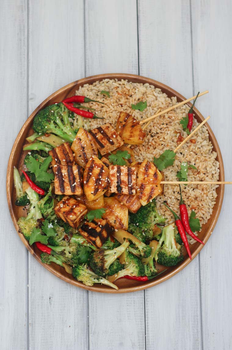 A plate of Tofu marinated and grilled on Skewers served with broccoli and rice