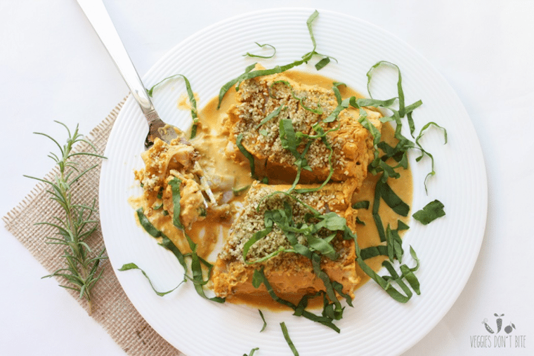 Birds eye view of butternut squash lasagna roll ups in a white bowl garnished with basil.