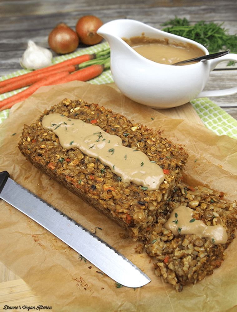 Two slices of lentil loaf drizzled with cashew gravy on parchment paper.