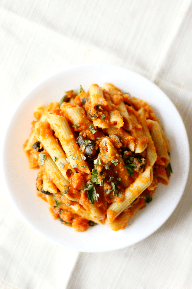 birds eye view of vegan pumpkin pasta on a white plate garnished with sage