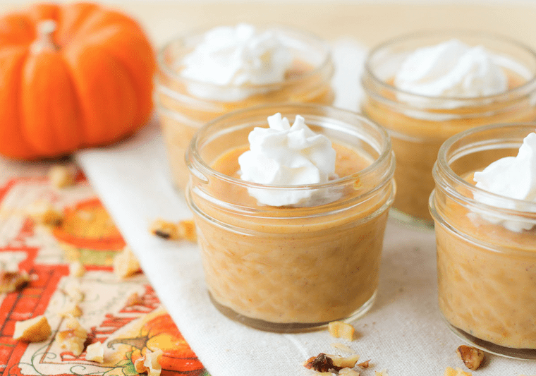 Pumpkin parfait in small mason jars garnished with whipped cream.
