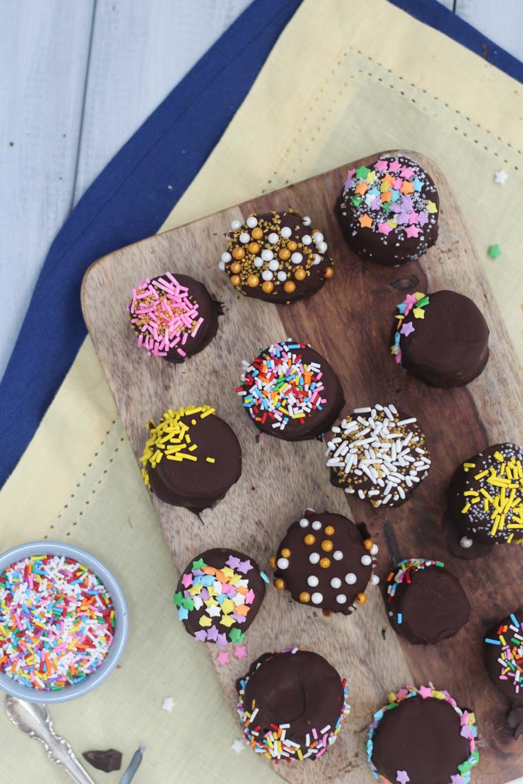 birds eye view of vegan paleo chocolate banana bites topped with colourful sprinkles on a wooden board