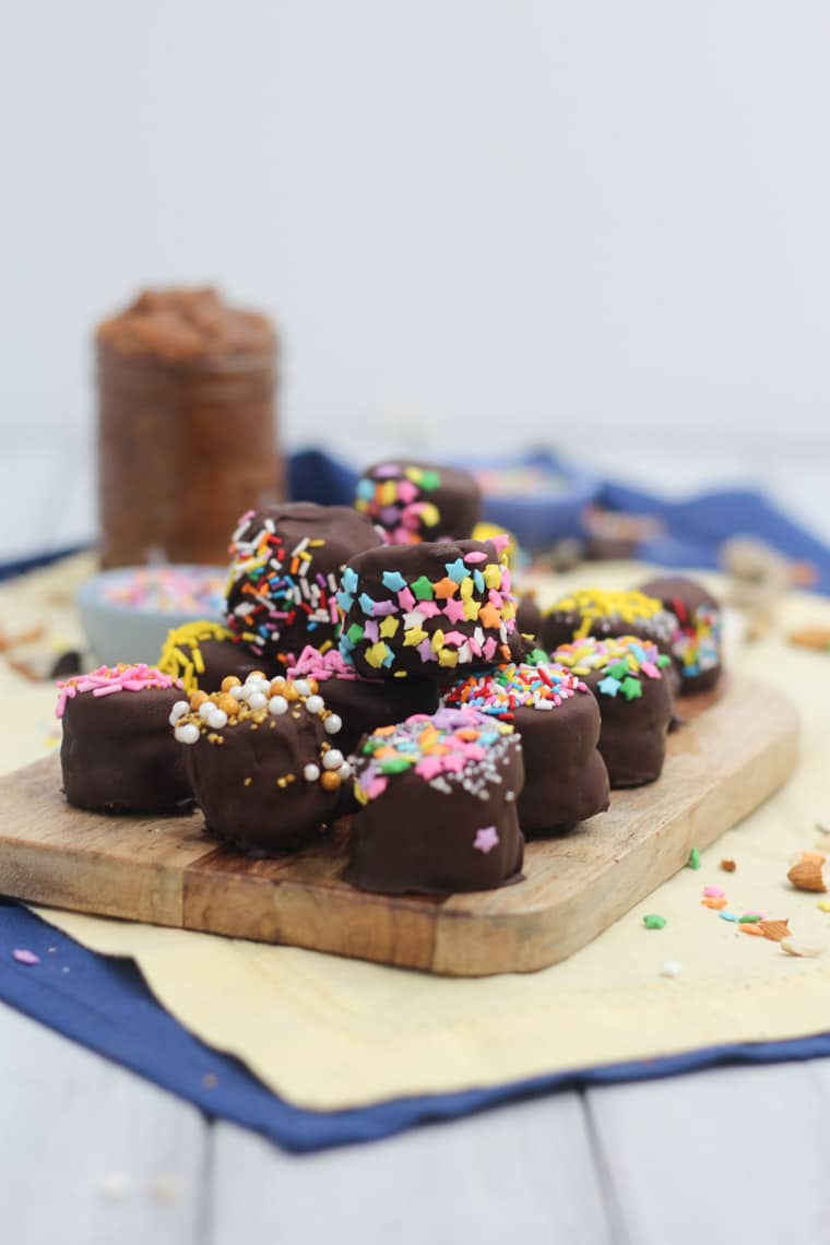 frozen chocolate dipped banana bites stuffed with almond butter on a wooden counter