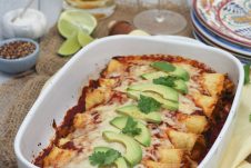 A white baking dish with chicken and butternut squash enchiladas.