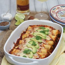 A white baking dish with chicken and butternut squash enchiladas.