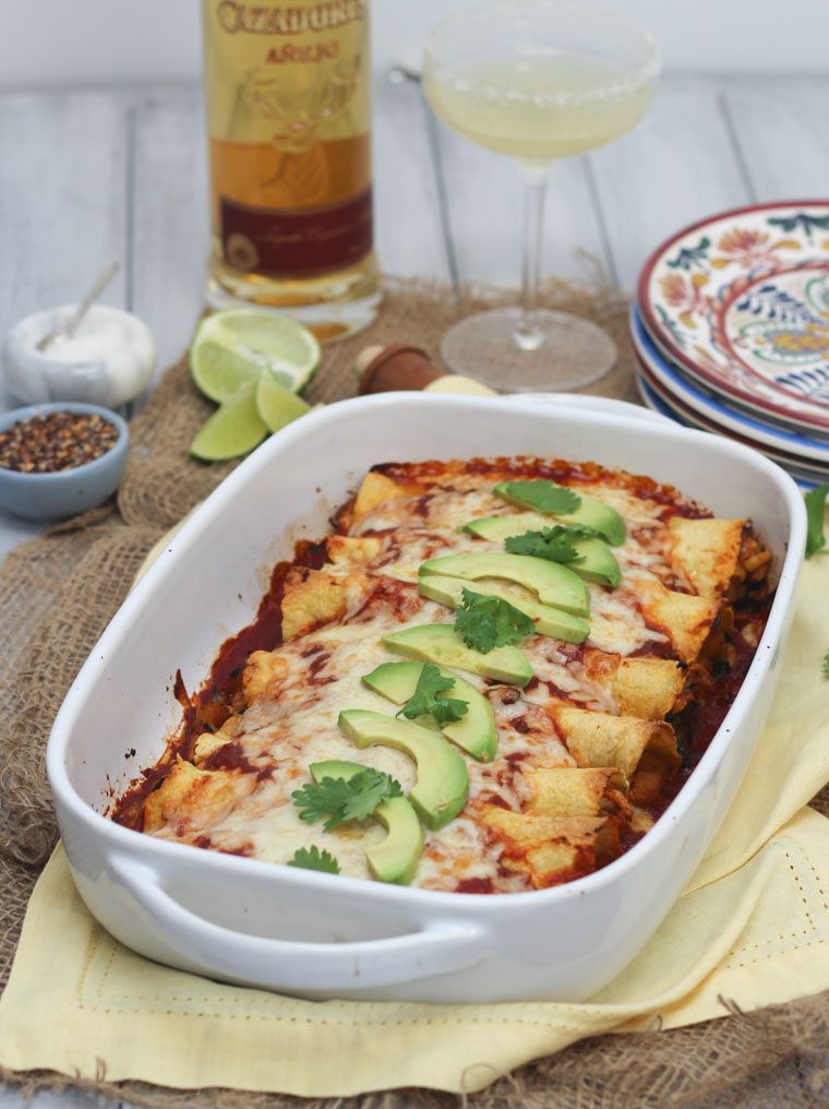 A white baking dish with chicken and butternut squash enchiladas.