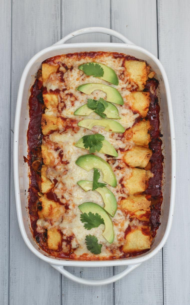 An overhead photo of a white baking dish with chicken and butternut squash enchiladas.