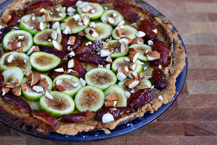 Fruit pie in a blue dish garnished with chopped nuts.