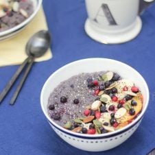 A bowl of quinoa with blueberries, bananas, and seeds on top.