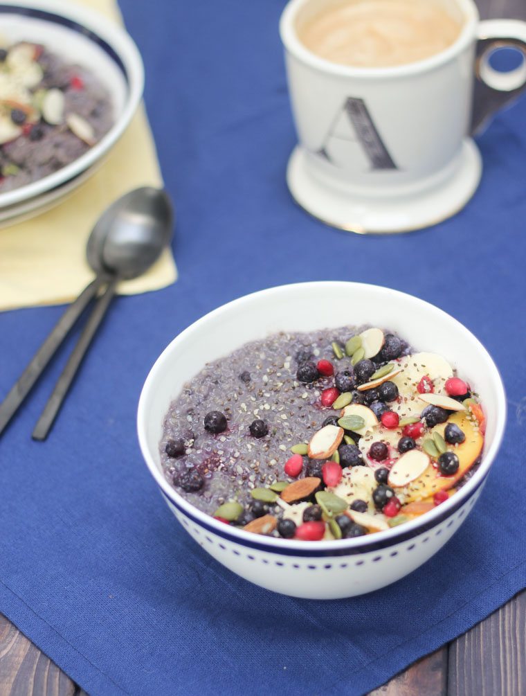 A bowl of quinoa with blueberries, bananas, and seeds on top.