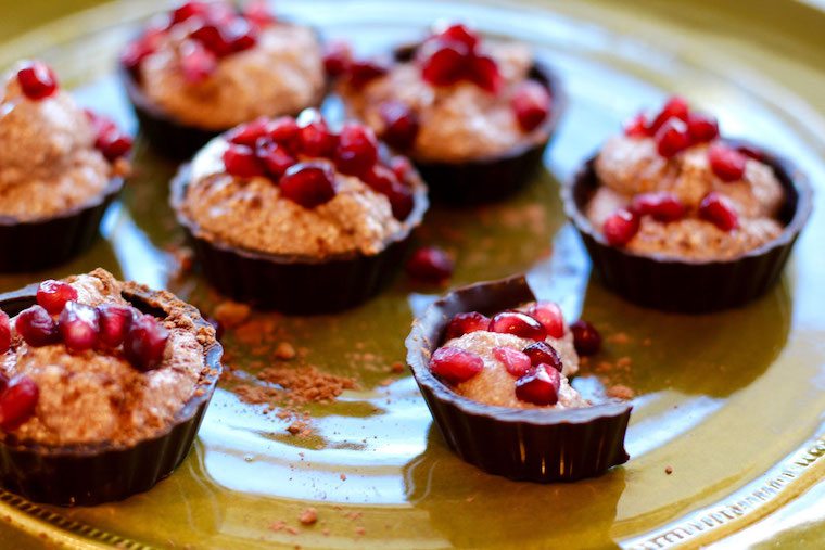 Chocolate cups on a plate garnished with fresh fruit.