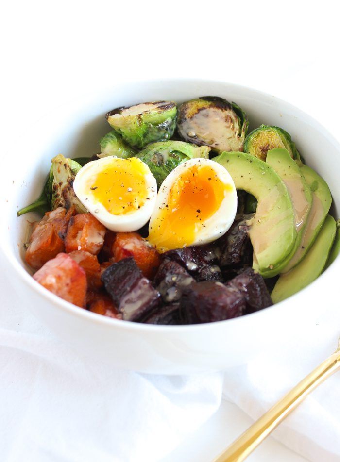 close up of paleo rainbow buddha bowl garnished with black pepper in a white bowl