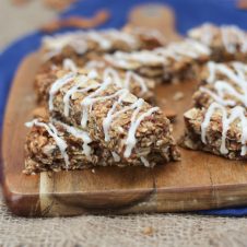 A close up image of multiple cinnamon bun granola bars on a brown cutting board.