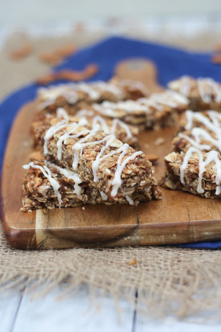 A close up image of multiple cinnamon bun granola bars on a brown cutting board.