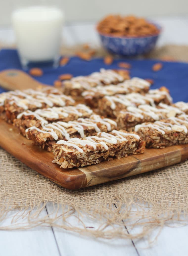 An angled image of multiple cinnamon bun granola bars on a brown cutting board.