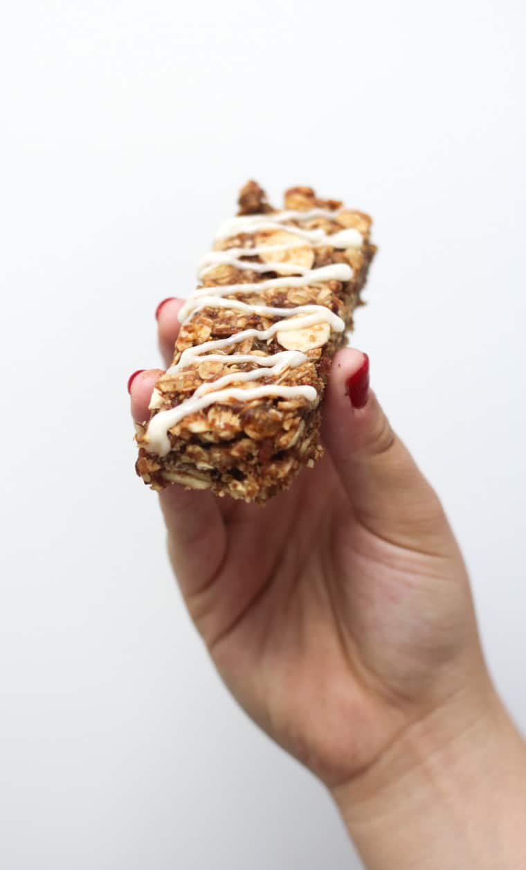 A hand holding up a cinnamon bun granola bar.