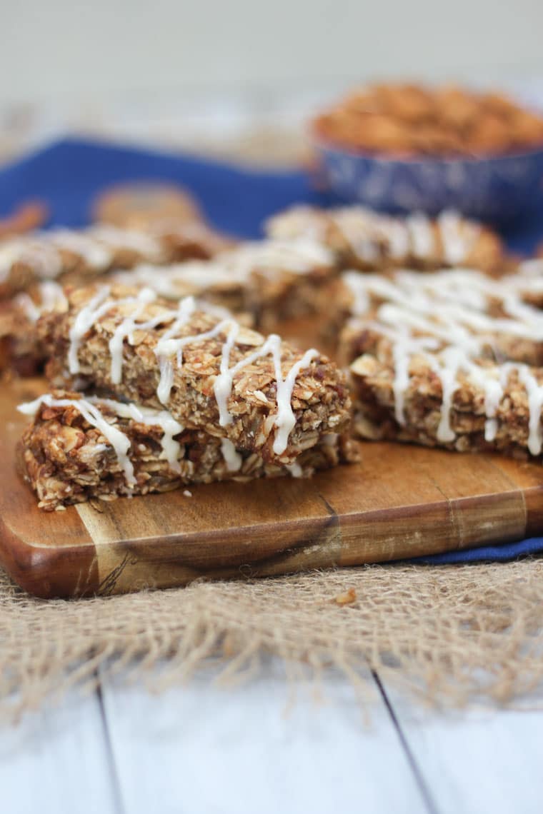 An angled image of multiple cinnamon bun granola bars on a brown cutting board.