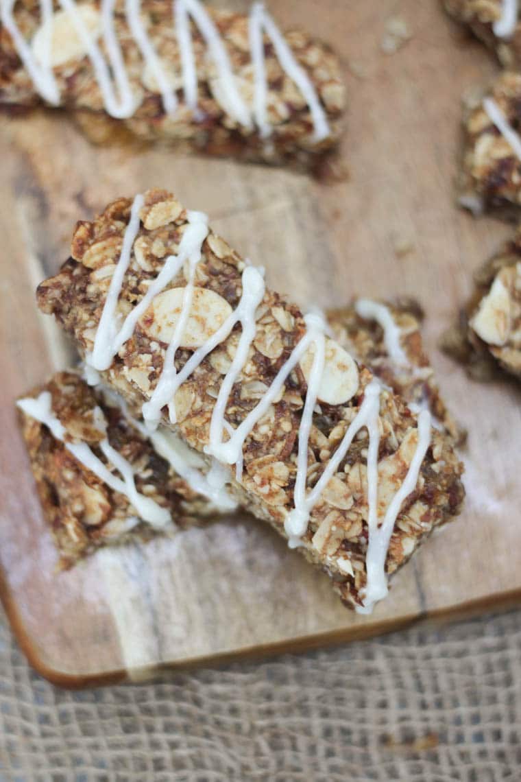 An overhead image of two cinnamon bun granola bars on a brown cutting board stacked on top of each other.