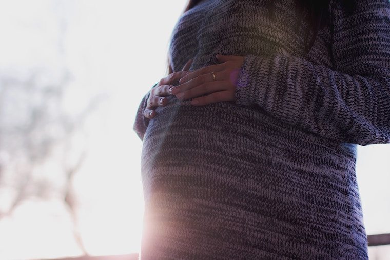 Person in a dress holding their baby bump