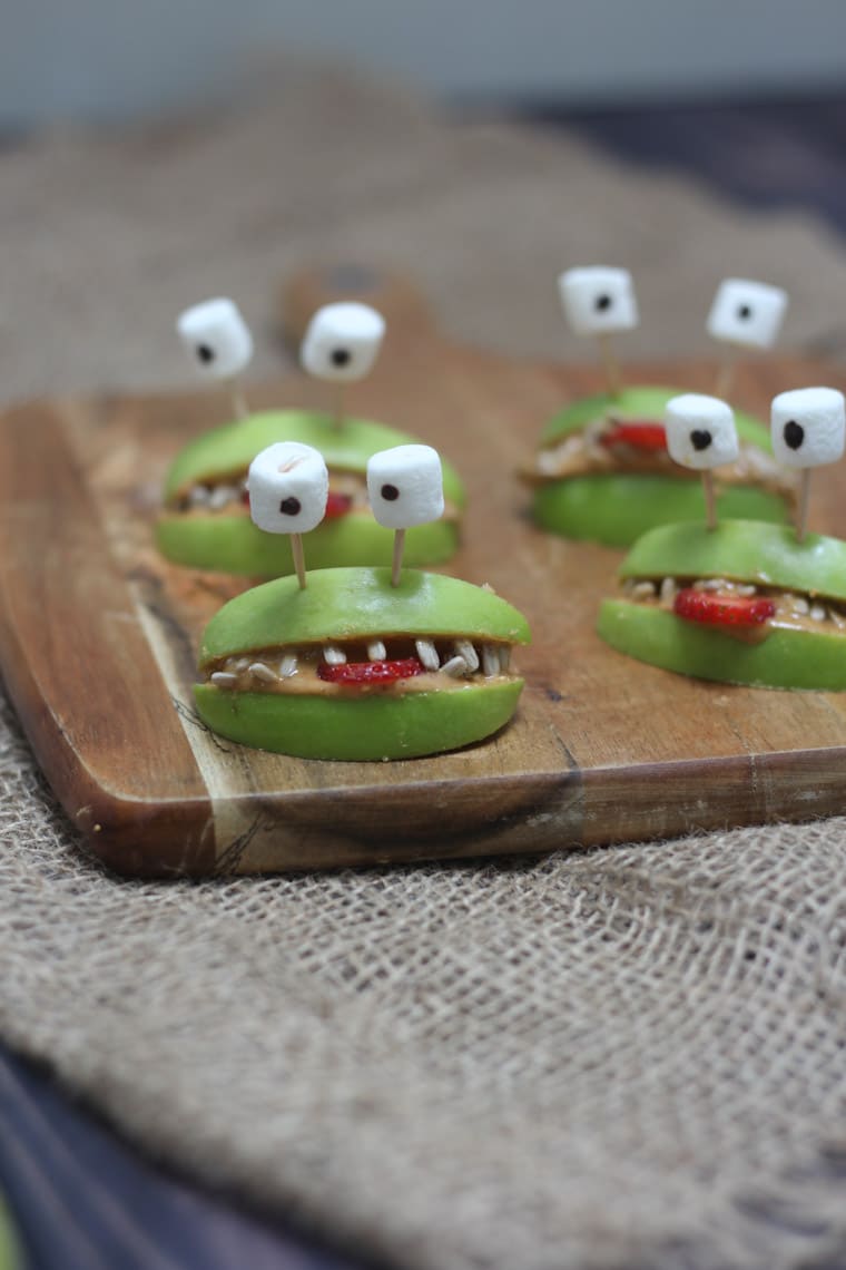 Four halloween apple alien smiles with marshmallow eyes.