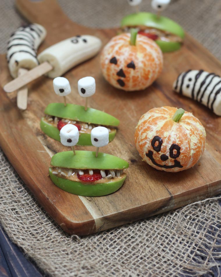 various vegan and gluten free halloween fruit treats on a wooden board