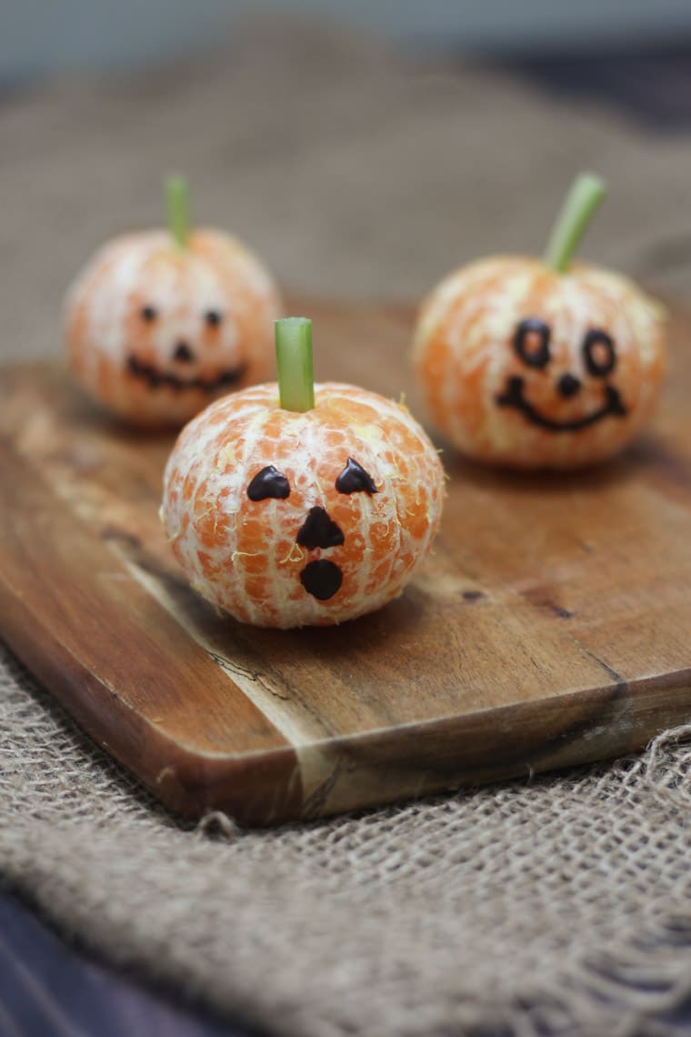 close up of three clementine pumpkins on a wooden board