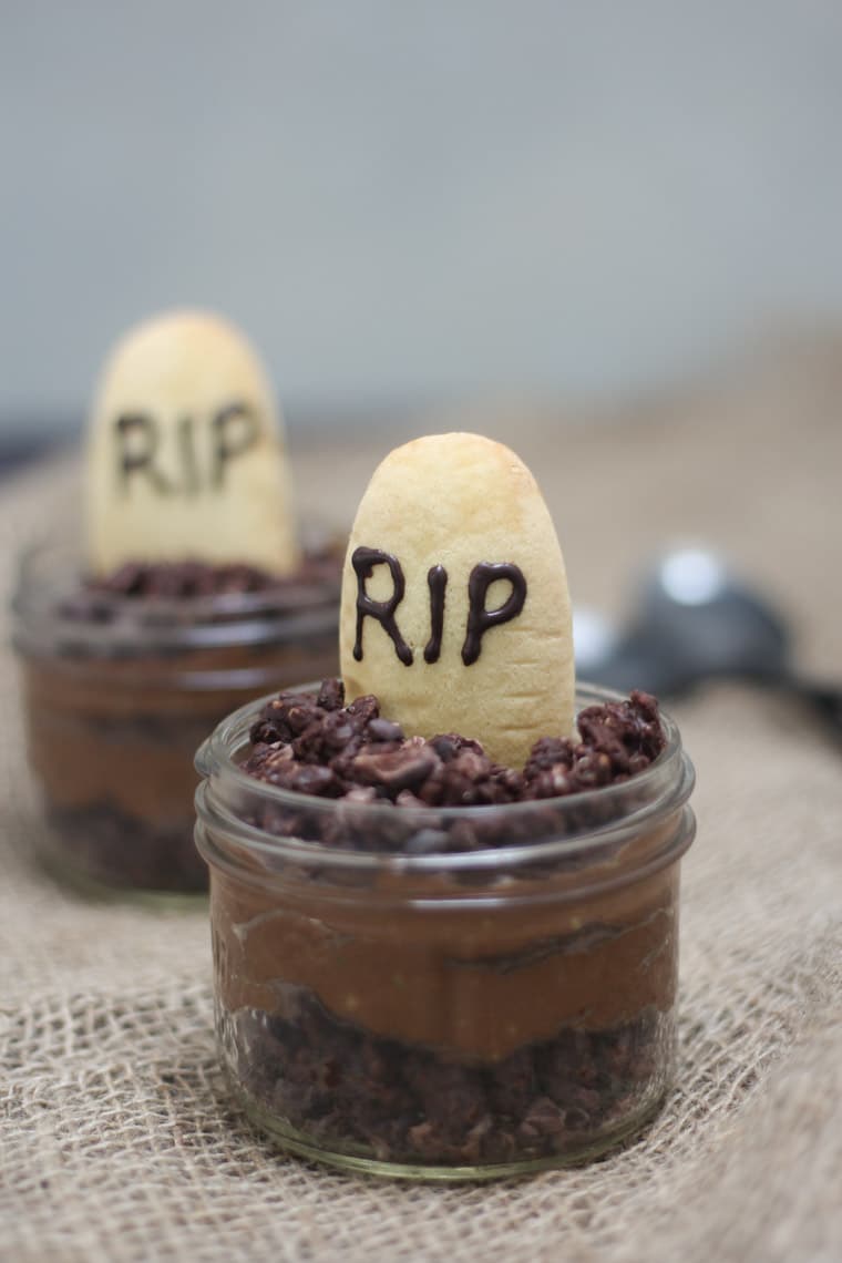 A close up of a Halloween graveyard mousse with an edible gravestone saying RIP in chocolate with a second one in the background.