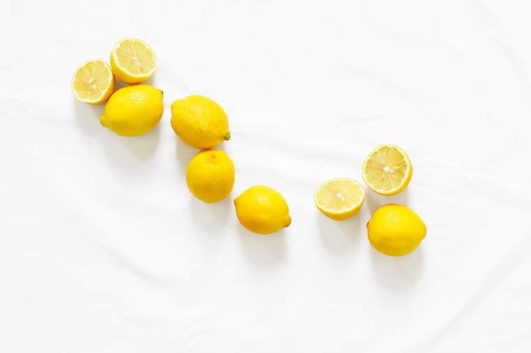 Multiple lemons on a white marble surface.