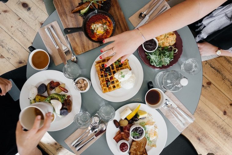 Hand reaching for a waffle from a brunch platter.