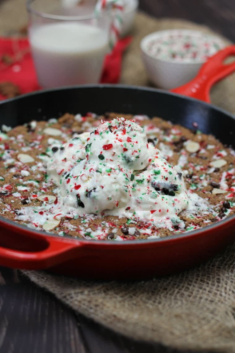 Large chocolate chip skillet cookie recipe in a pan topped with ice cream and candy canes. 