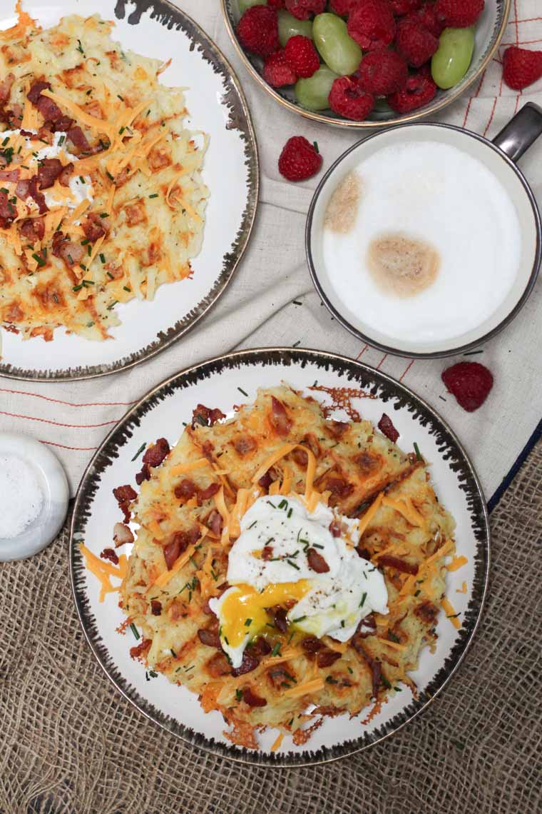 An overhead image of a plate of a loaded potato waffles with an egg on top.